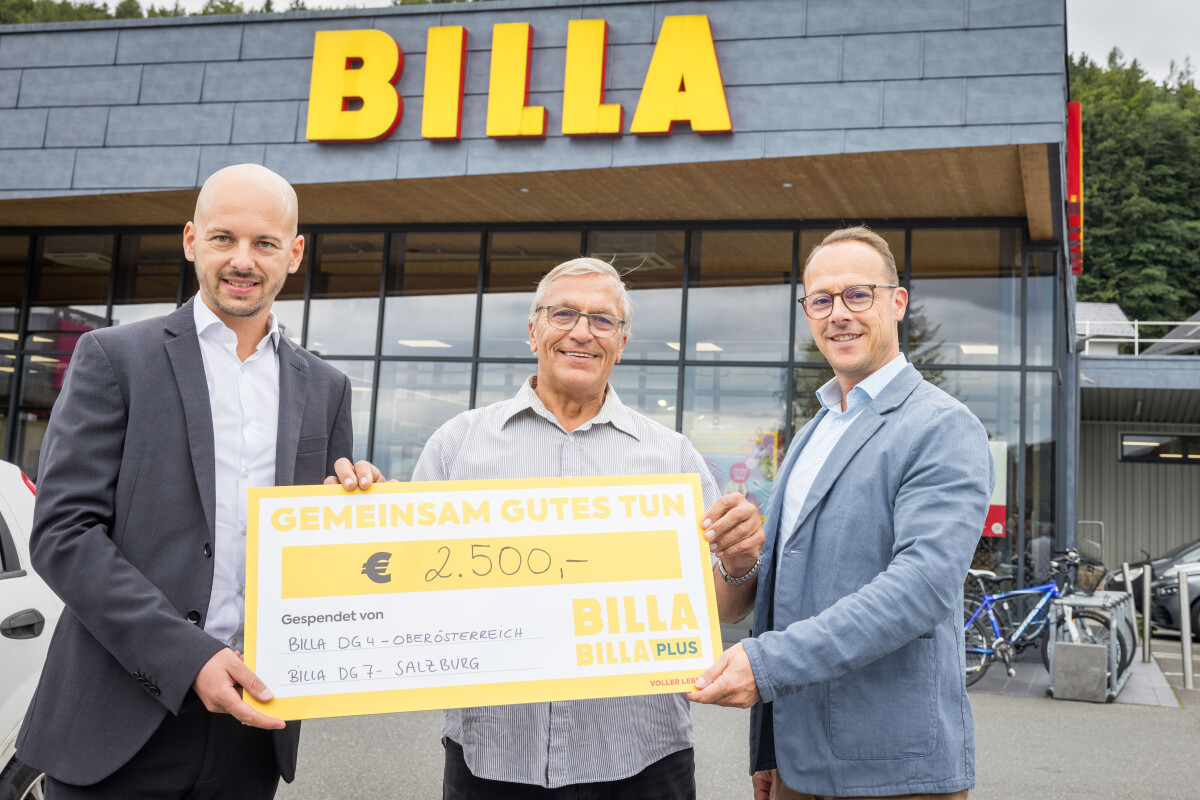 Drei Männer halten einen großen Scheck über 2.500 Euro vor einer BILLA-Filiale. Der Scheck hat die Aufschrift "Gemeinsam Gutes tun". Alle drei lächeln in die Kamera. Im Hintergrund ist das Gebäude und das BILLA-Logo zu sehen.
