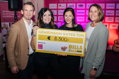 Vier Personen halten einen großen Scheck mit der Aufschrift „Gemeinsam Gutes Tun“ und einem Betrag von 8.500 Euro. Im Hintergrund Logos von Sponsoren auf einer Wand. Alle lächeln in die Kamera.