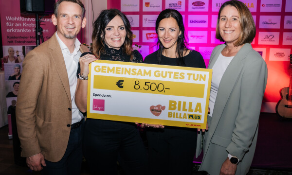 Vier Personen halten einen großen Scheck mit der Aufschrift „Gemeinsam Gutes Tun“ und einem Betrag von 8.500 Euro. Im Hintergrund Logos von Sponsoren auf einer Wand. Alle lächeln in die Kamera.
