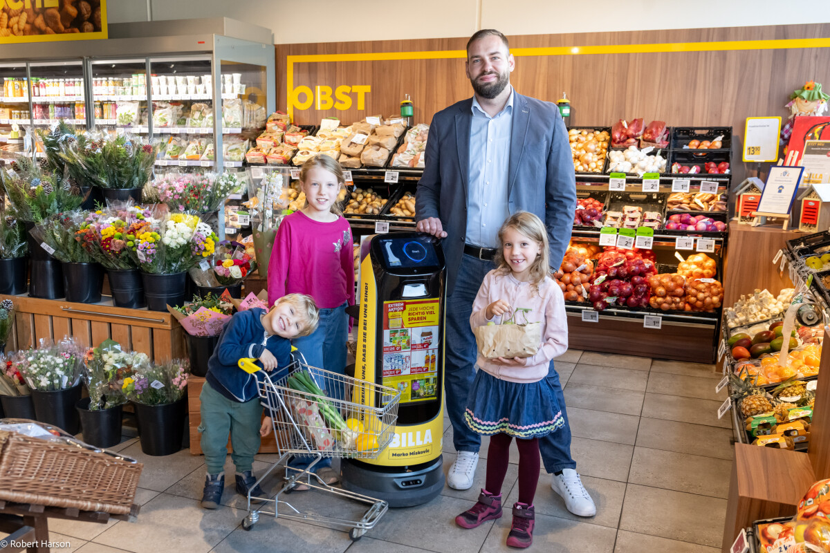 BILLA Kaufmann Marko Miskovic freut sich zusammen mit seinen kleinen Kund:innen über den Support der Roboter in seinem Markt in Gloggnitz.