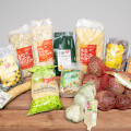 An assortment of organic food products arranged on a wooden table, including various grains, seeds, and vegetables like ginger, sauerkraut, and onions. Packaging features a mix of clear plastic and colorful labels with the word "Bio."