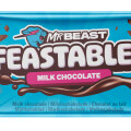 A blue MrBeast Feastables milk chocolate wrapper featuring chunks of chocolate and branding text. The label includes translations for "milk chocolate" in multiple languages.