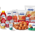 A variety of "clever" brand grocery products, including potato chips, oils, beverages, pasta, rice, ketchup, chopped tomatoes, eggs, and packaged meats, displayed in an organized manner.
