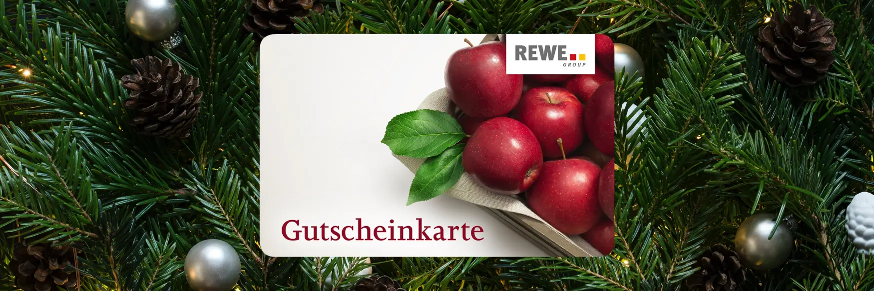 Gutscheinkarte der REWE GROUP Österreich vor Tannenzweigen