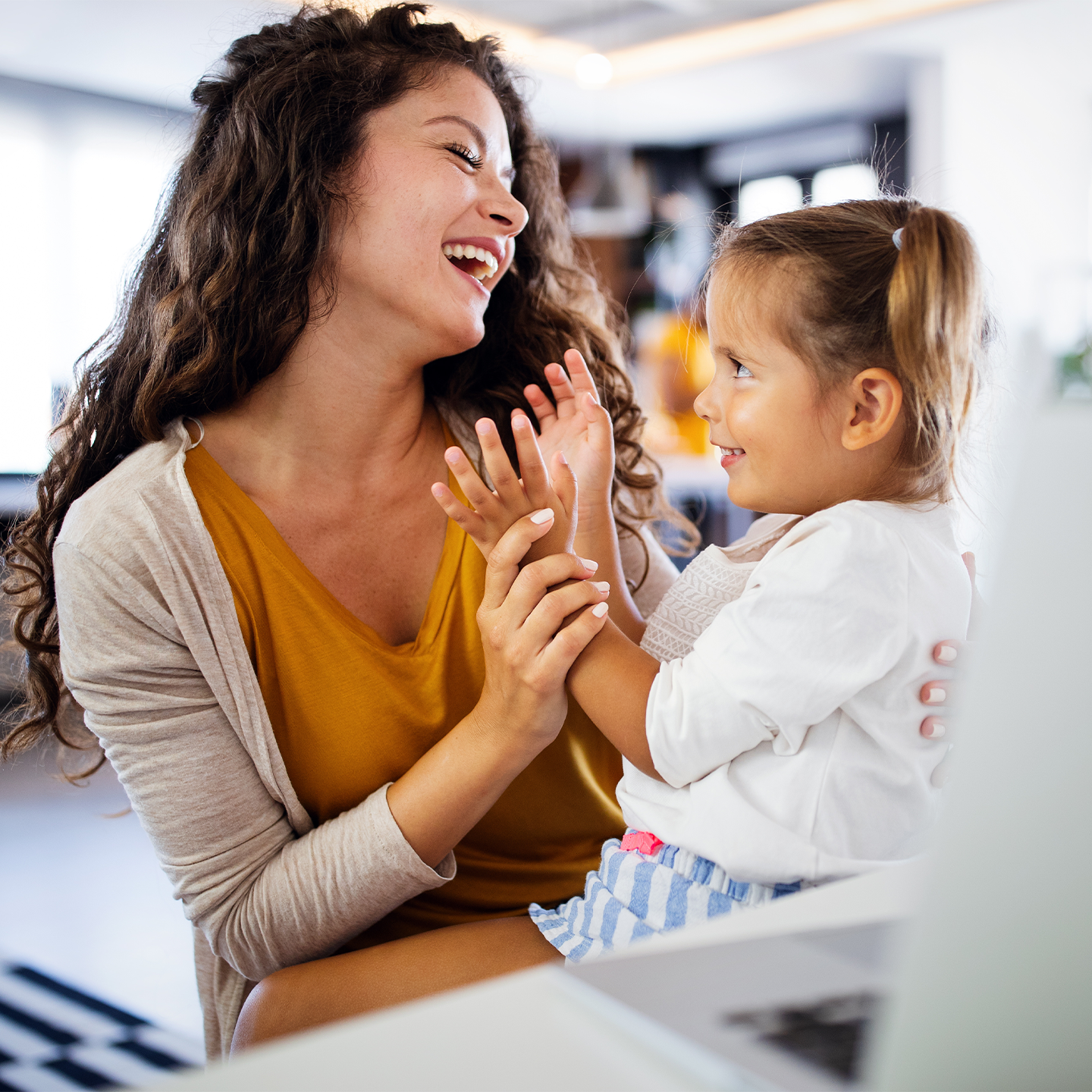 Dame sitzt lachend mit ihrer Tochter vor dem Laptop