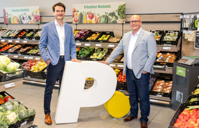 PENNY Geschäftsführer Johannes Greller und Niko Karras stehen mit großem "P." in der Obstabteilung einer PENNY Filiale